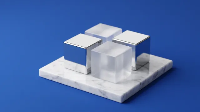 Four cubes in a two-by-two square on a white marble slab, two in polished chrome and two in frosted glass, on a cobalt blue background.