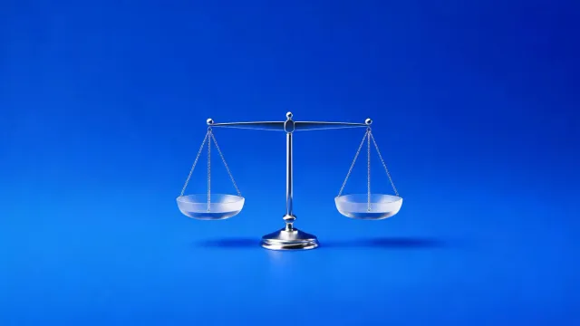 A chrome balance scale with two glass pans held level, on a blue background.