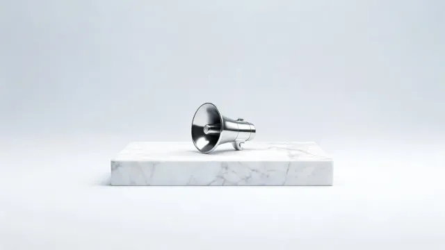 A chrome megaphone resting on a wide white marble plinth, on a light grey background.