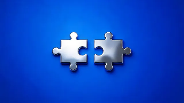 Two chrome puzzle pieces side by side, on a blue background.