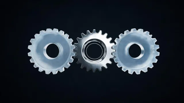 A chrome gear between two frosted-glass gears, on a black background.